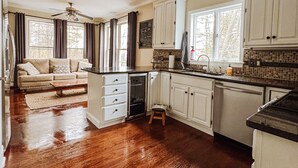 A spacious kitchen with wooden flooring, white cabinets, and a built-in oven. - Maine Luxury Home On the Sea (Brunswick)