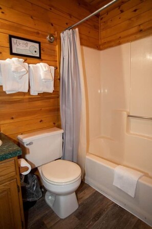 A wooden cabin bathroom with a toilet, shower, and a towel rack. - Cabin 2307 - Cozy Log Cabin within Private Resort (Gaylord)