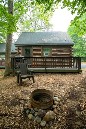 Une cabane en rondins avec un foyer et un banc.