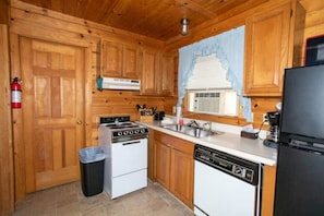 Una cocina con gabinetes de madera, estufa, lavavajillas y refrigerador.