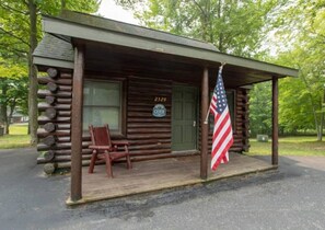 Een blokhut met een veranda, een bank, een Amerikaanse vlag en een bord met het nummer 2329.