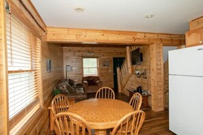 Un interior de madera con una mesa de comedor, sillas, un sofá y un refrigerador.