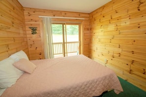 A wooden cabin room with a bed, a window, and a door leading to an outdoor area. - Cabin 2364 - Sizable Log Cabin within Private Resort (Bagley Township)
