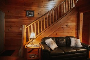 A wooden interior with a leather sofa, a lamp, and a staircase.