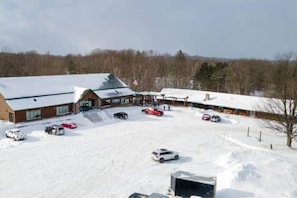 A building with a snow-covered parking lot and several cars.