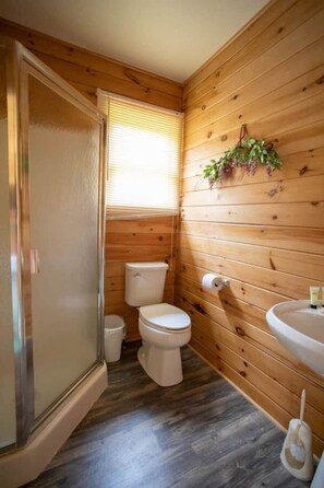 Ein kleines Badezimmer mit Holzvertäfelung, Toilette, Bidet und Waschbecken.