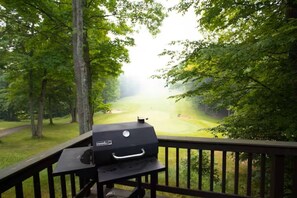 Un barbecue installé sur une terrasse donnant sur un terrain de golf.