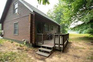 Une cabane en rondins avec une vĂ©randa et des marches menant Ă lâentrĂ©e.