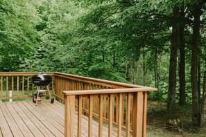 A wooden deck with a barbecue grill. - Cabin 2353 - Little Log Cabin within Private Resort (Bagley Township)