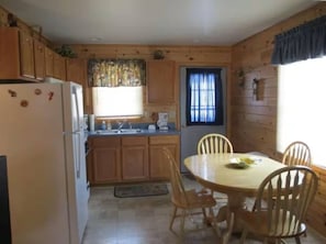 Ein Holzblockhaus-Interieur mit KĂŒche, Esstisch und StĂŒhlen.