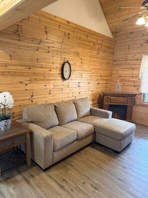 A cozy room with a wooden ceiling, a fireplace, and a sofa.