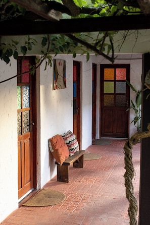 A covered outdoor area with a bench, a wooden door, and a colorful window.