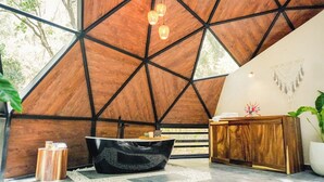 Ein modernes Interieur mit einer geometrischen Holzzahlendecke, einer schwarzen Badewanne und einem Holzbüro.