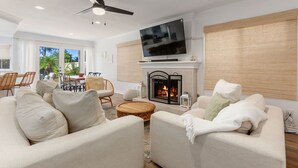 Un salon avec une cheminée, un téléviseur et un ventilateur de plafond.