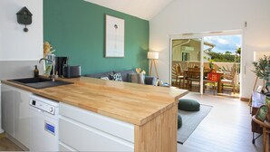 A modern kitchen with a wooden countertop, a built-in dishwasher, and a green accent wall. - 2CH Orient-Bay beach walk (Orient-Baie)