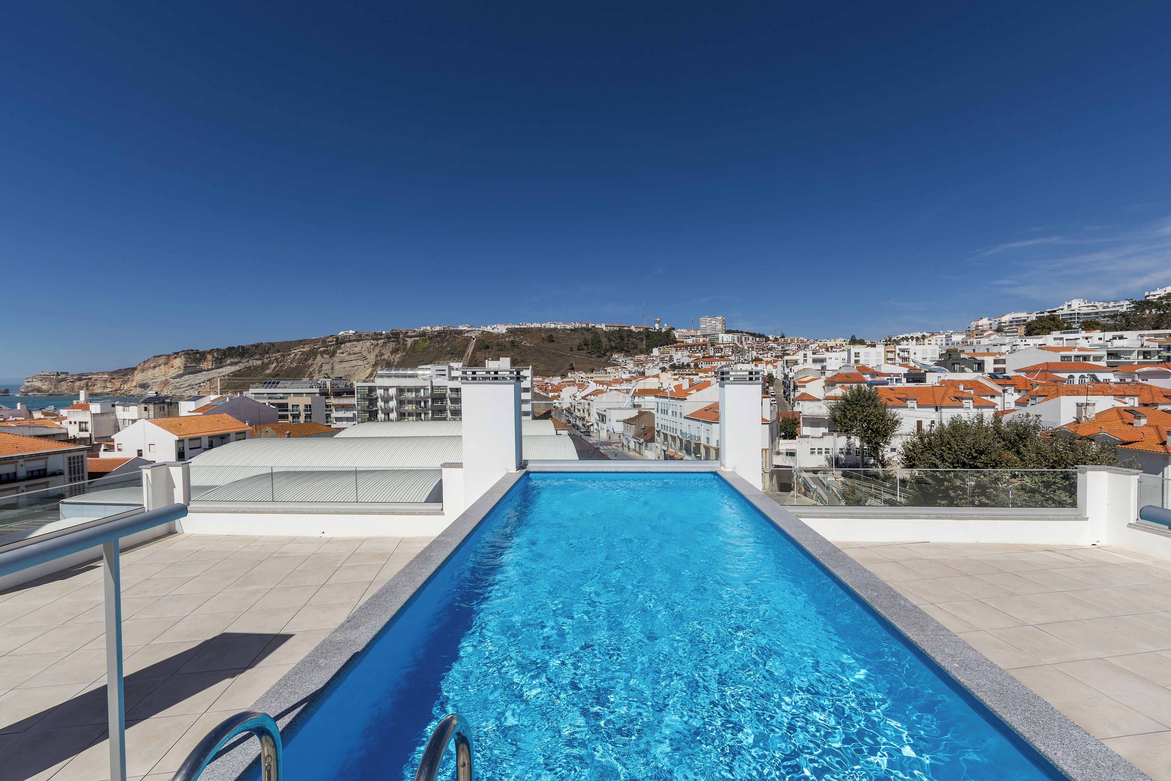 A swimming pool with a clear view of a coastal town in the background.