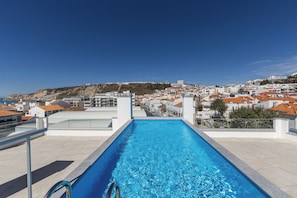 A swimming pool with a clear view of a coastal town in the background.