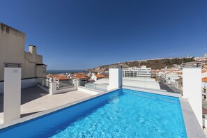 Une piscine sur le toit offrant une vue dégagée sur le paysage urbain et la côte.