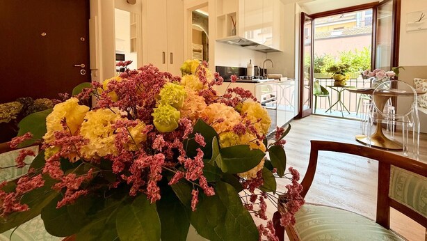 Una cocina moderna con armarios blancos, una estufa a la vista y un comedor con mesa y sillas.