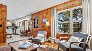 A cozy living room with wooden walls, a dining area, and a kitchen. - Bayview Beach Cottage For 4! (Saco)