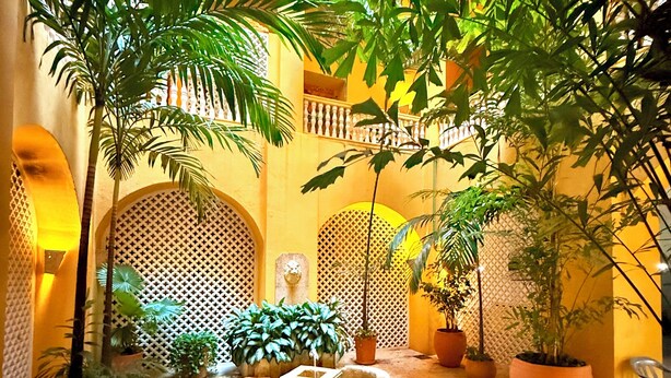 A courtyard with a water feature, potted plants, and a seating area. - by Calamari Homes - El Porvenir (Cartagena)