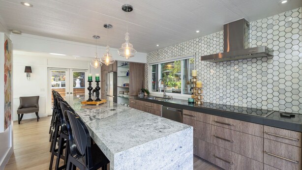A modern kitchen with a large island, wooden cabinets, and a hexagonal tile backsplash. - Tranquil Home in Coto de Caza (Coto de Caza)