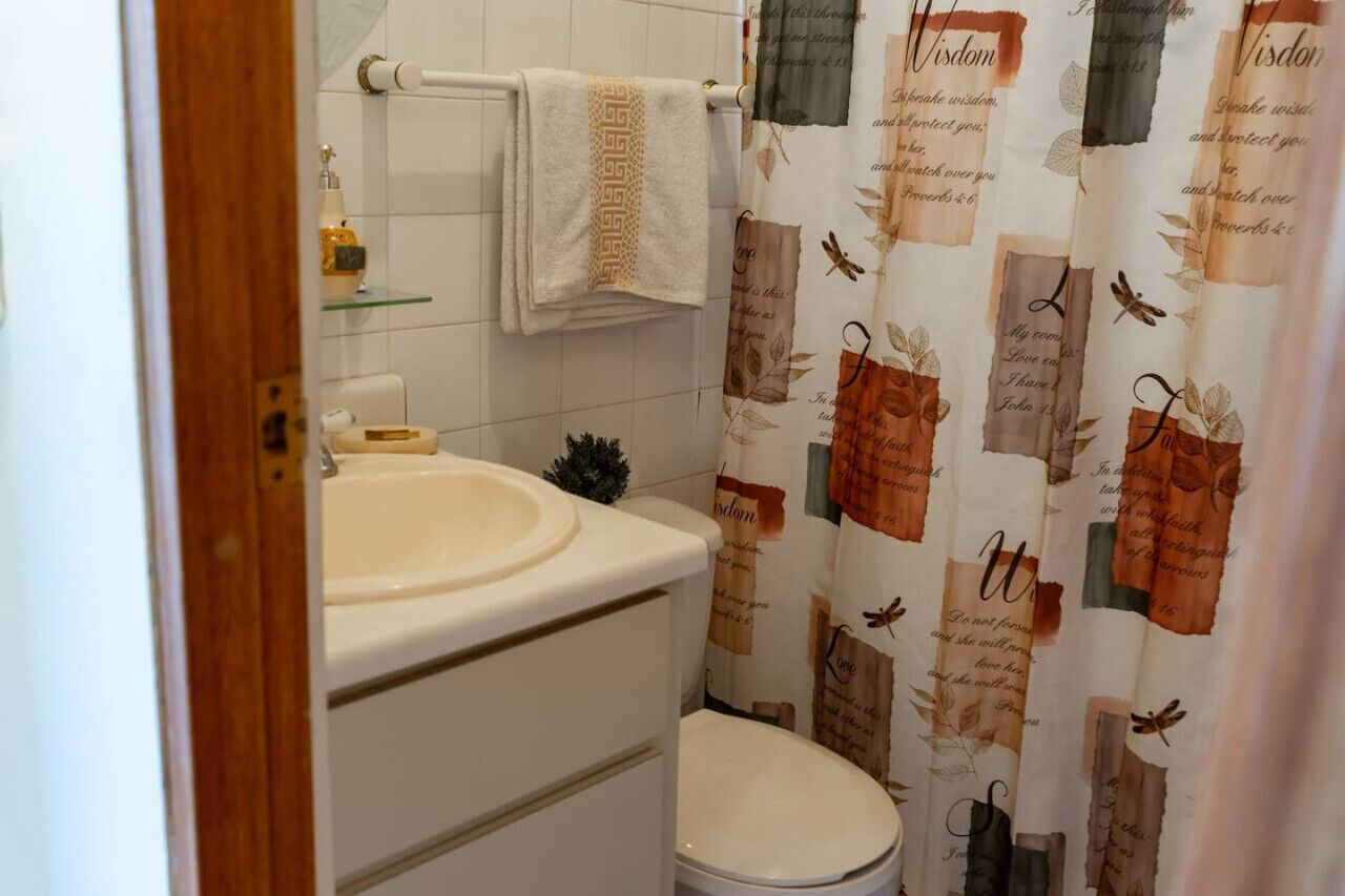 Un baño con lavamanos blanco, inodoro y perchero para toallas.