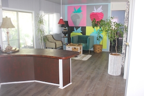 Un salon moderne avec une table basse en bois aux lignes courbes, un fauteuil turquoise, un lampadaire et un grand tableau mural.