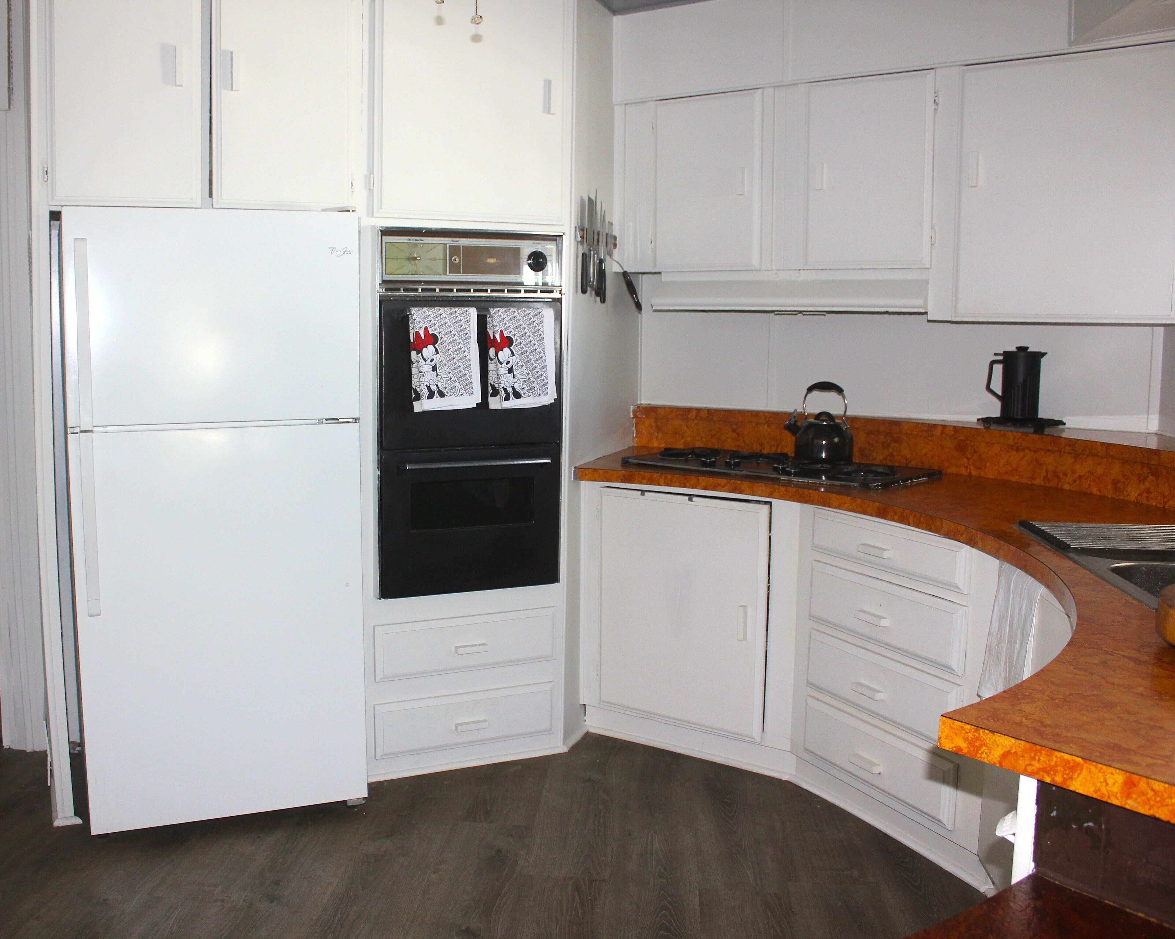 Una cocina con armarios blancos, un horno negro, una estufa y un refrigerador.