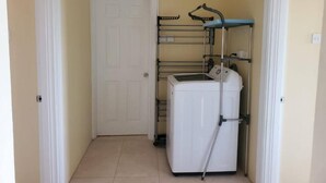 Une buanderie équipée d’un lave-linge, d’un étendoir et d’une porte.
