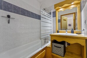A bathroom with a glass shower enclosure, a wooden vanity with a sink, and a mirror above the vanity.