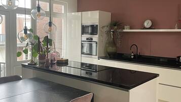 Een koelkast, een oven, een vaatwasser, kookgerei, borden en bestek