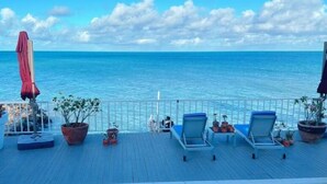 A deck with lounge chairs and potted plants overlooking the sea. - Ocean Garden Studio 2 (St Johns)