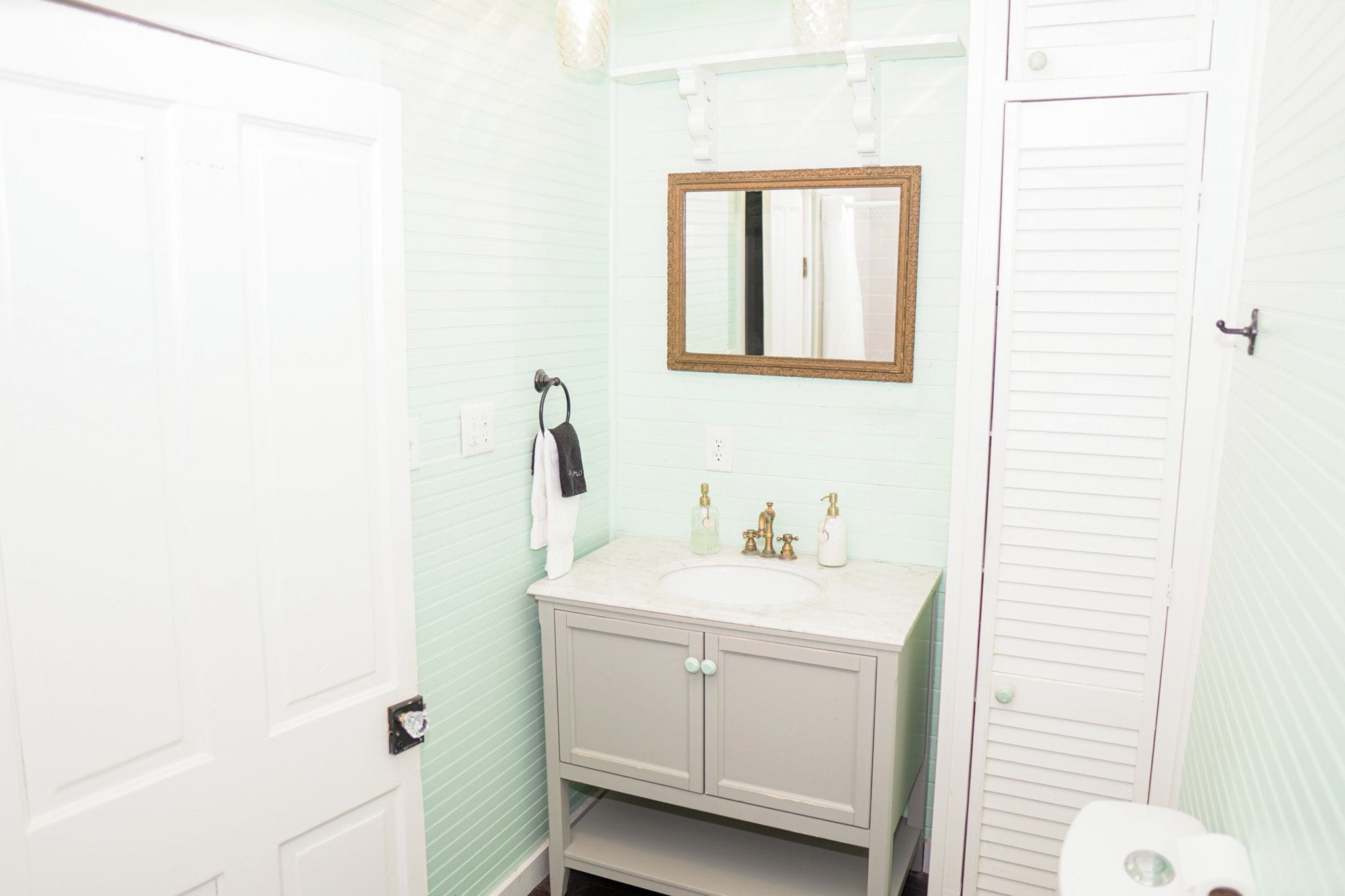 Une salle de bain avec une porte blanche, un meuble-lavabo avec un miroir et des toilettes.