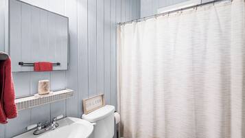 Ein Badezimmer mit einem weißen Waschbecken, einer Toilette, einem Spiegel und einer Duschvorhang.