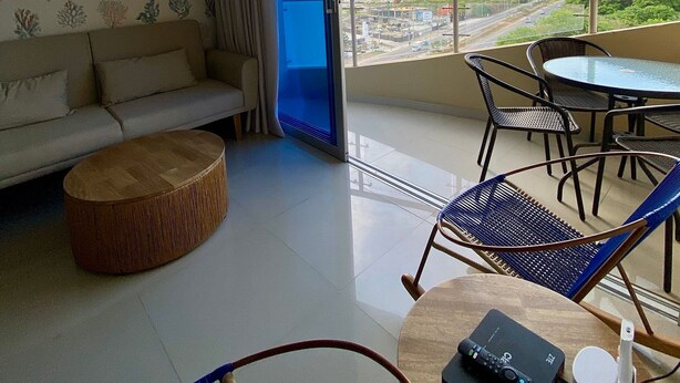 A living room with a sofa, a round coffee table, and a balcony with a view of buildings and a construction site. - U-GO Edificio Oasis (Santa Marta)