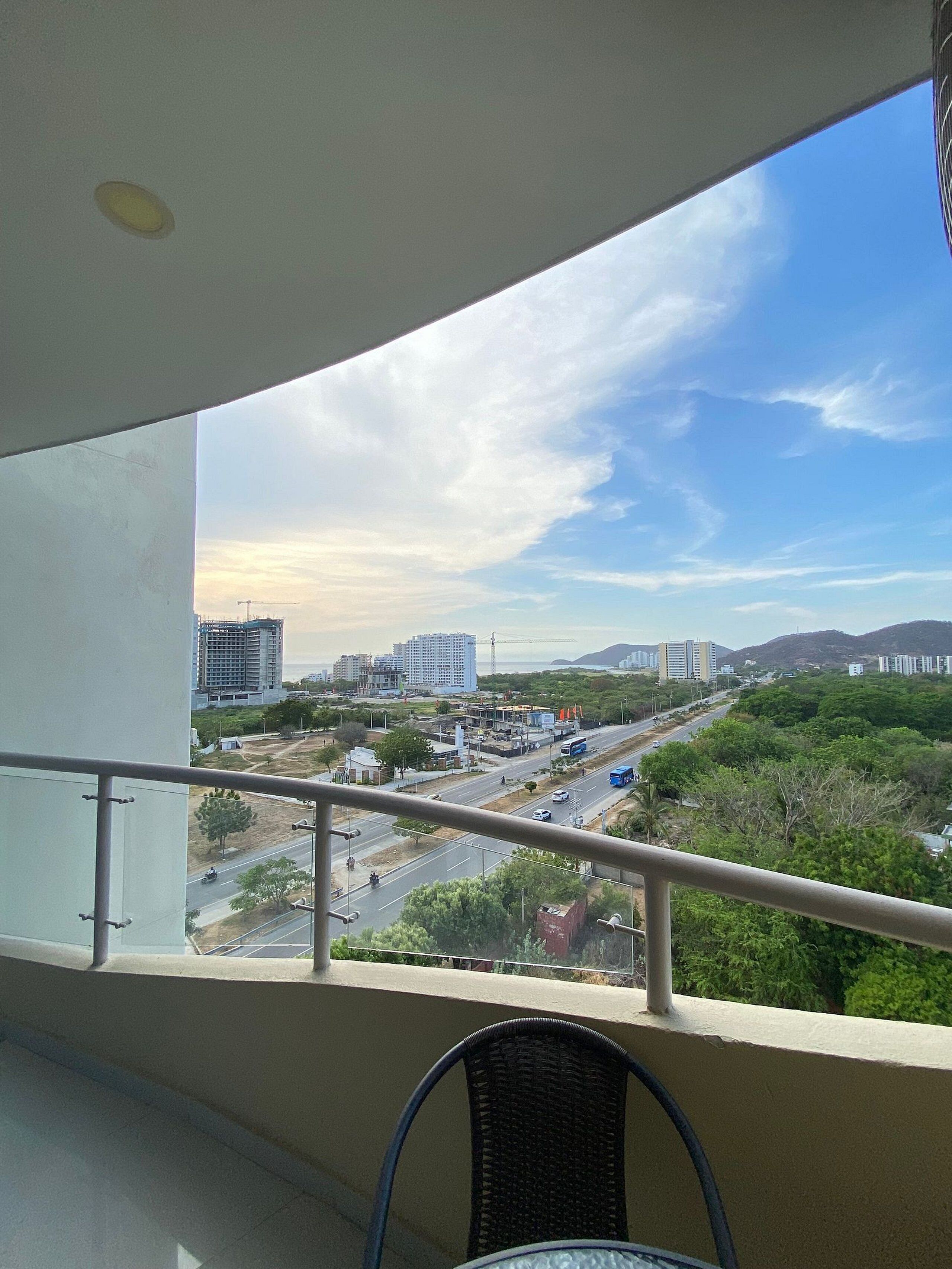 Un balcón con vista a un paisaje urbano, que incluye edificios y una carretera.