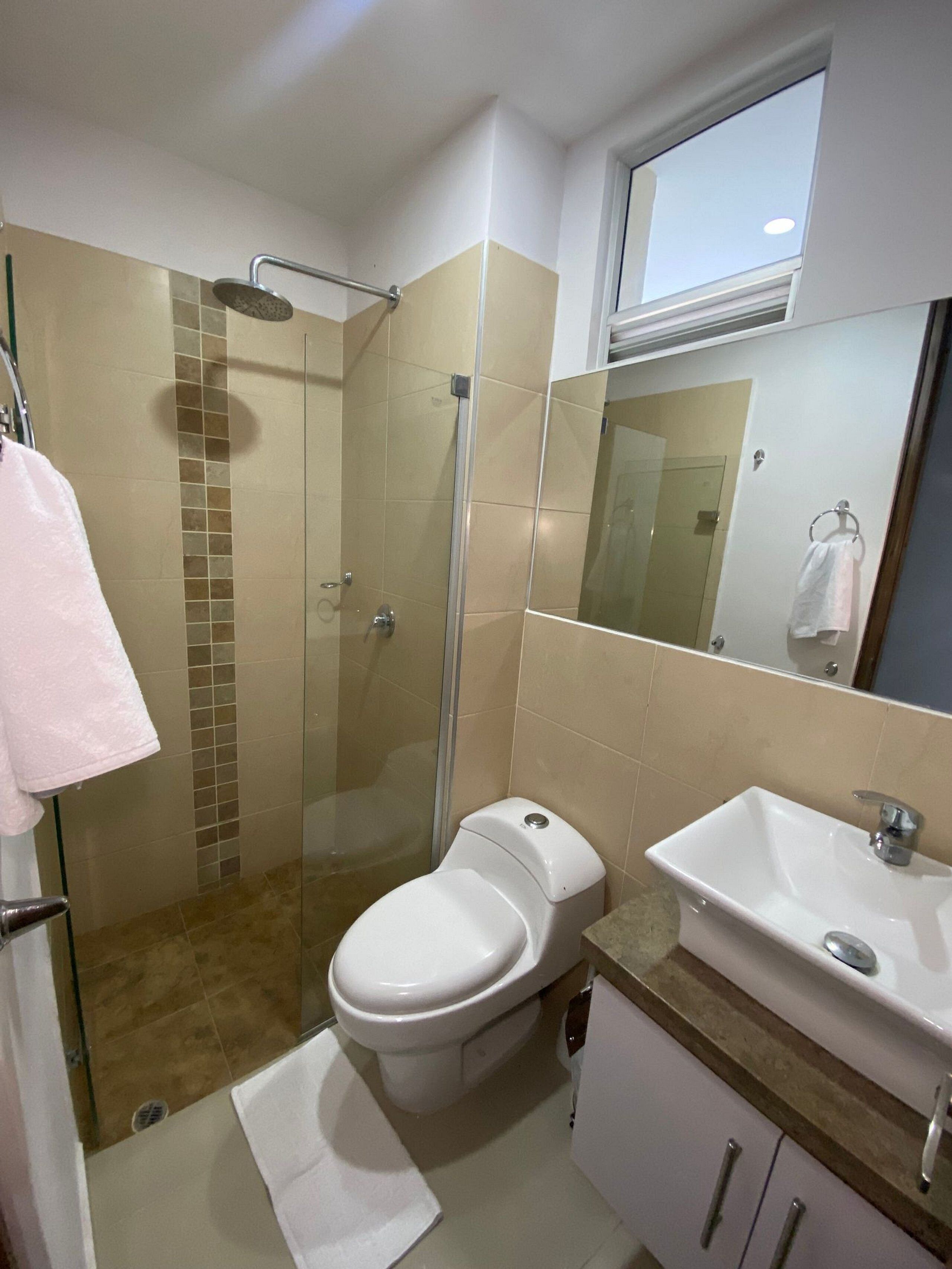 Une salle de bain équipée d’une douche, de toilettes, d’un lavabo et d’un miroir.