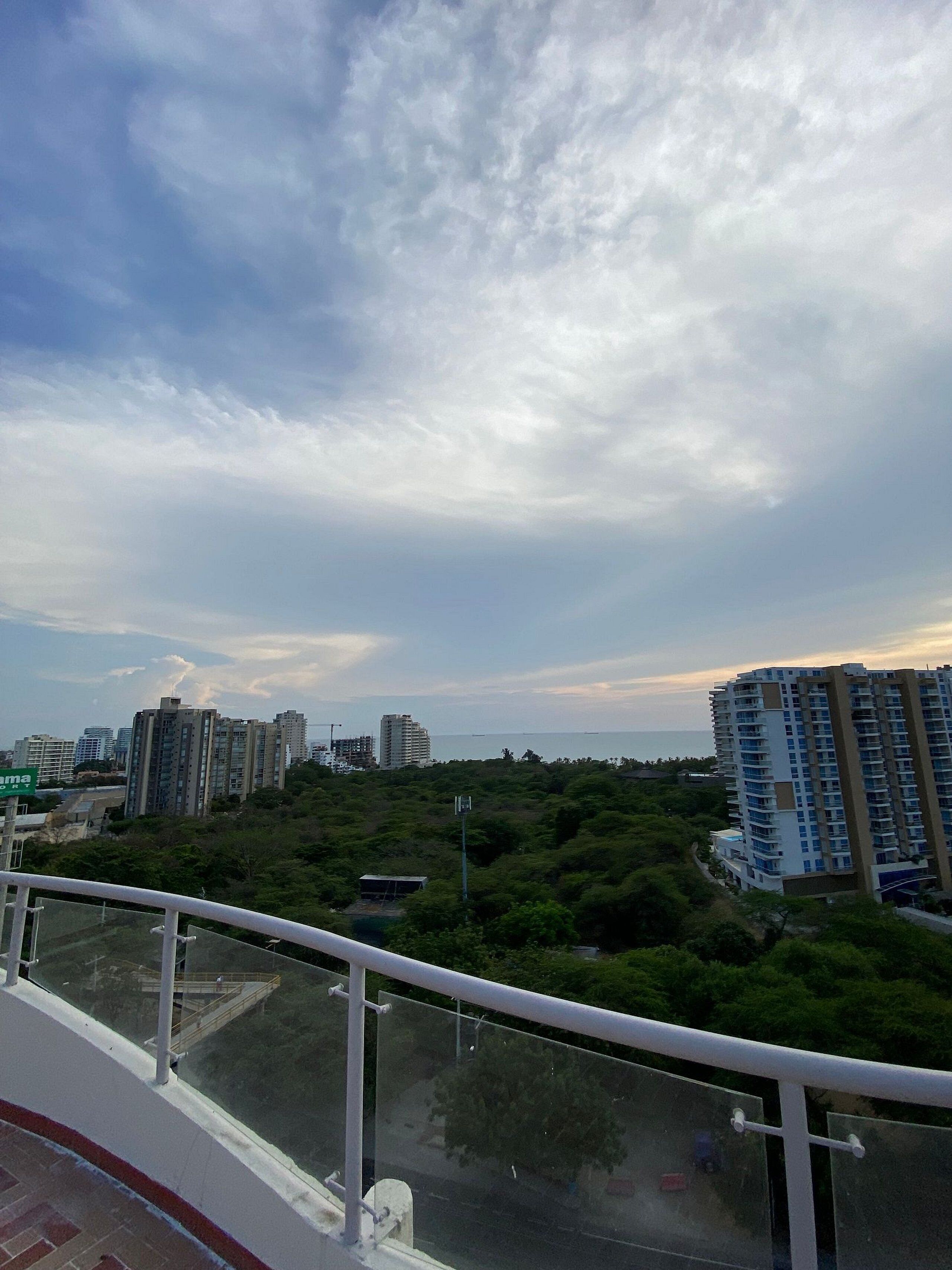 A high-rise building with a view of the sea and surrounding greenery.