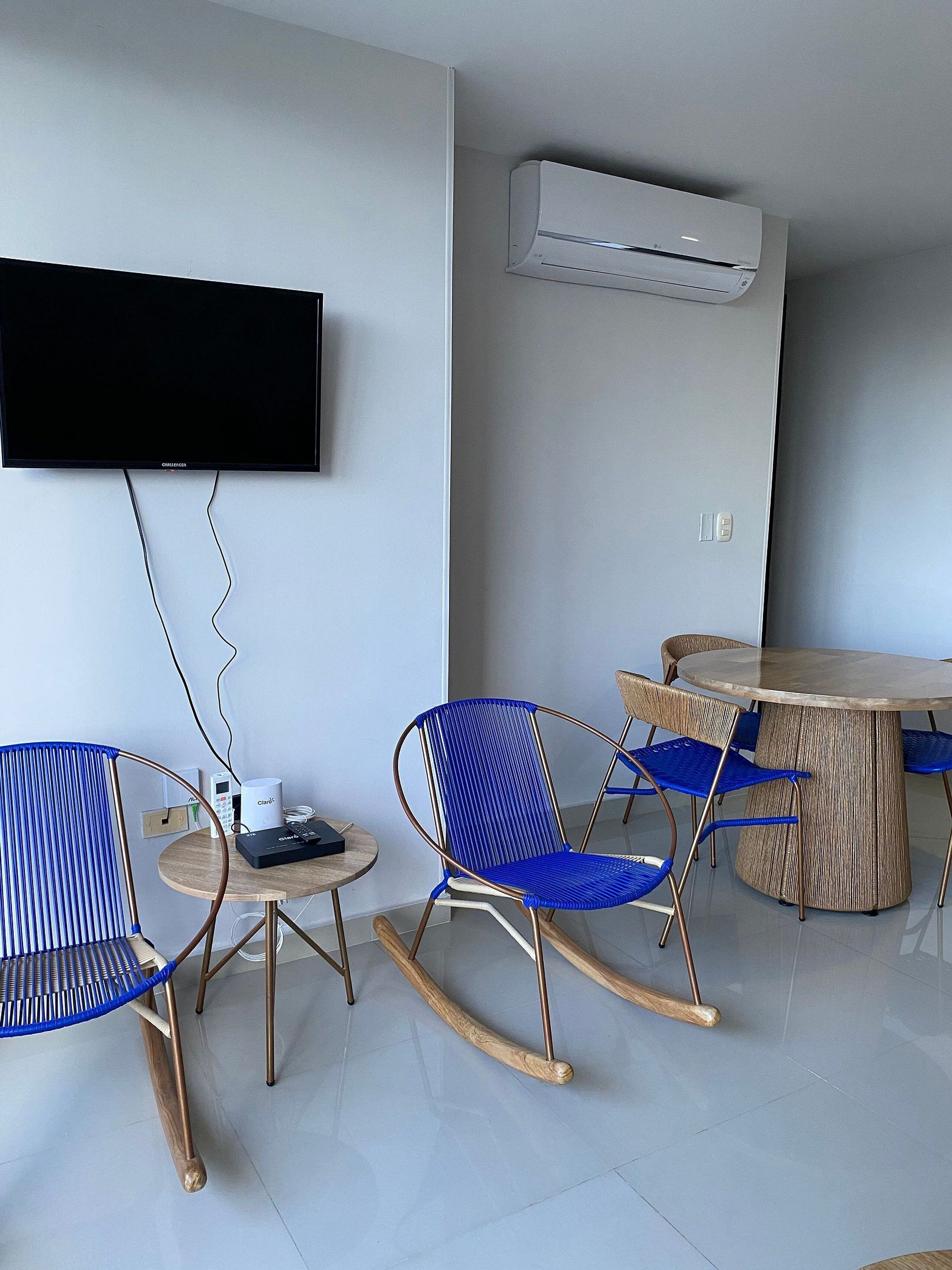 Une chambre moderne équipée d’un téléviseur à écran plat, d’une table ronde avec des chaises et d’un appareil de climatisation.