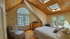 A bedroom with a large bed, a chair, a dresser, and a skylight. - South Beach | Katama | Outdoor Shower  ☀️ 🏖 (Edgartown)