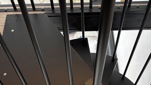A spiral staircase with black metal railings and a marble floor.