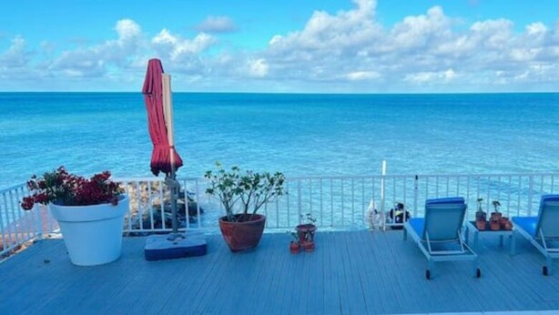 A deck with lounge chairs and potted plants overlooking the sea. - Ocean Garden Studio I (St Johns)