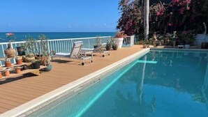 A poolside area with lounge chairs and potted plants. - Ocean Garden Studio I (St Johns)