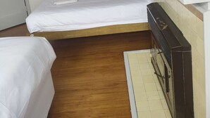 Una habitación pequeña con una cama individual, suelo de madera, pared blanca y televisor empotrado.