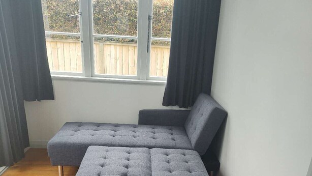 Un sofá seccional gris en una habitación con piso de madera y un ventanal grande.