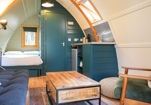 A cozy interior with a bed, a wooden table, a sofa, and a small kitchenette. - Deluxe Cosy Cabin in the Scottish Highlands (Tomintoul)
