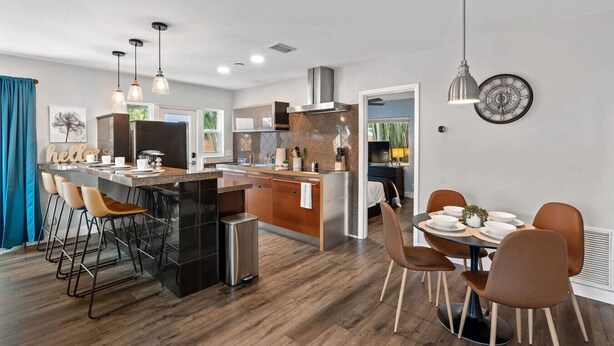 A modern kitchen with a central island, bar stools, and a dining area with a round table and chairs. - Pet-Friendly 1BR | Full Kitchen | Fenced Yard (Fort Lauderdale)