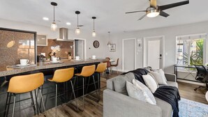 A modern kitchen with a granite countertop, bar stools, pendant lighting, and a ceiling fan. - Pet-Friendly 1BR | Full Kitchen | Fenced Yard (Fort Lauderdale)