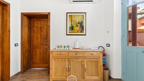 Een houten kast met lades, erboven een lijstwerk schilderij, en een betegelde vloer.